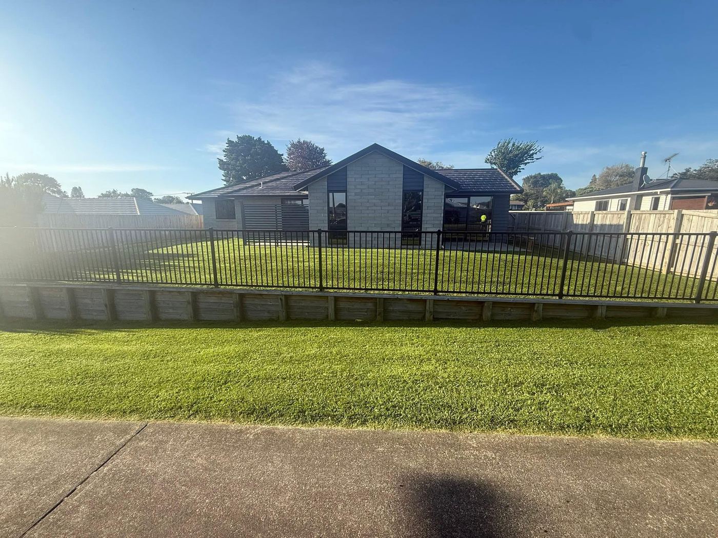 Fenced section lawn mowing with palm trees by JR Lawn Mowing